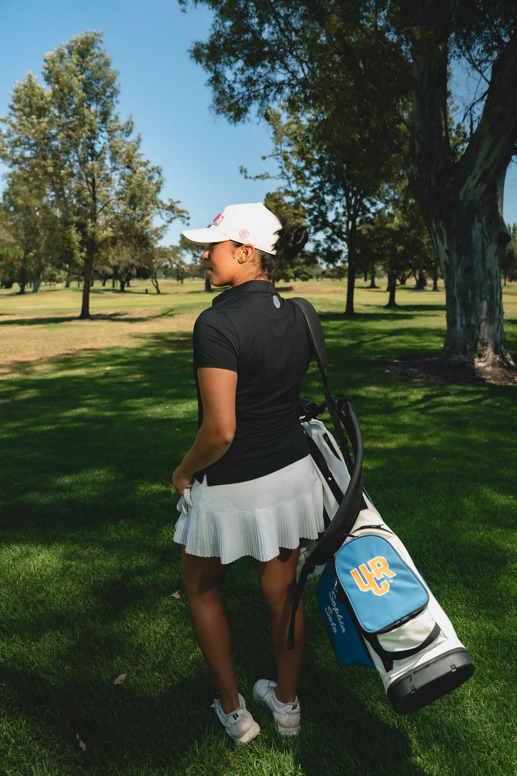 Woman golfer carrying her golf bag in Kingsmen golf apparel